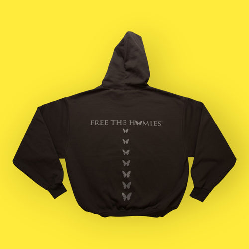 Black hoodie with 'FREE THE HOMIES' text and butterfly design on a yellow background